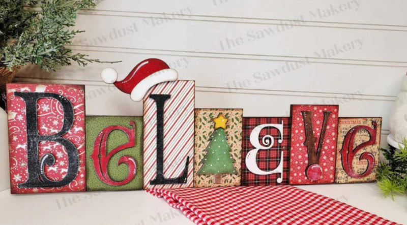 Christmas-themed decorative letters spelling 'BELIEVE' on a wooden surface with festive decorations.