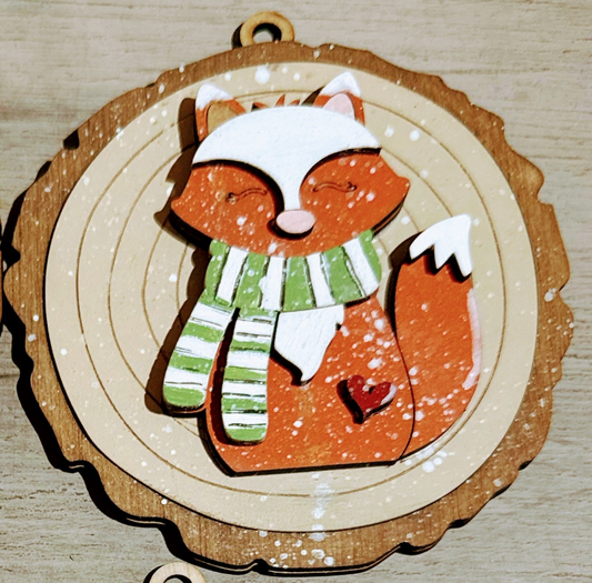 Wooden ornament with a fox design wearing a hat and scarf on a wooden surface.