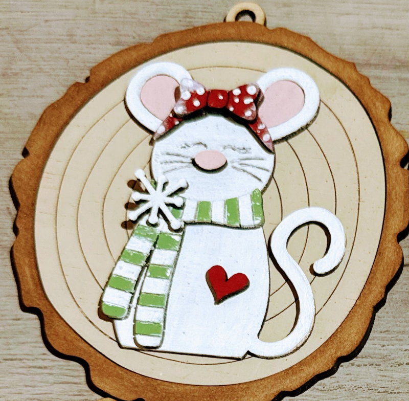 Decorative mouse ornament with a red bow, green scarf, and heart on a wooden background